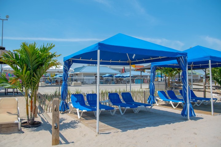 a playground with a blue umbrella sitting on top of a sandy beach