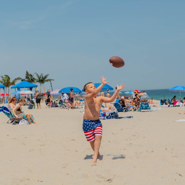 a group of people playing frisbee on a sandy beach
