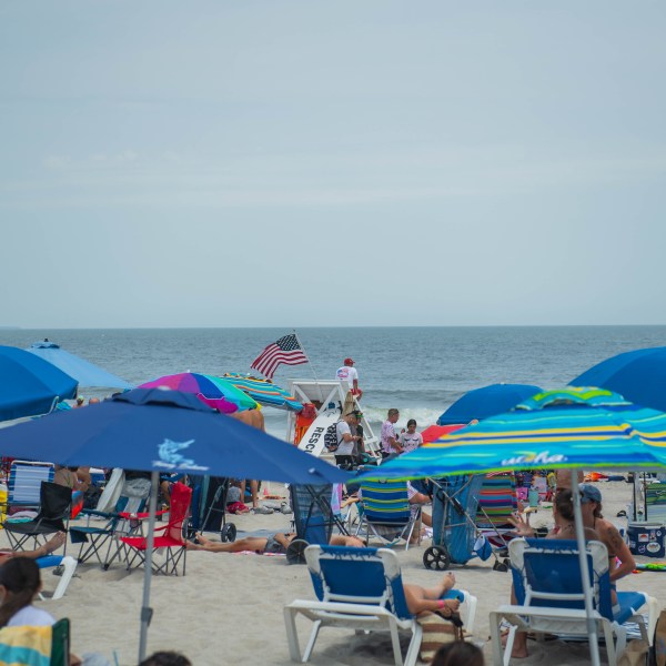 a group of people sitting at a beach umbrella in the sand