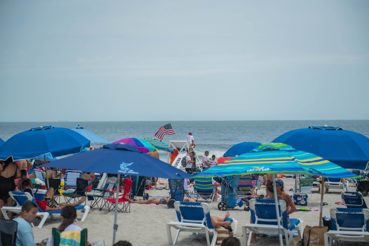 a group of people sitting at a beach umbrella in the sand
